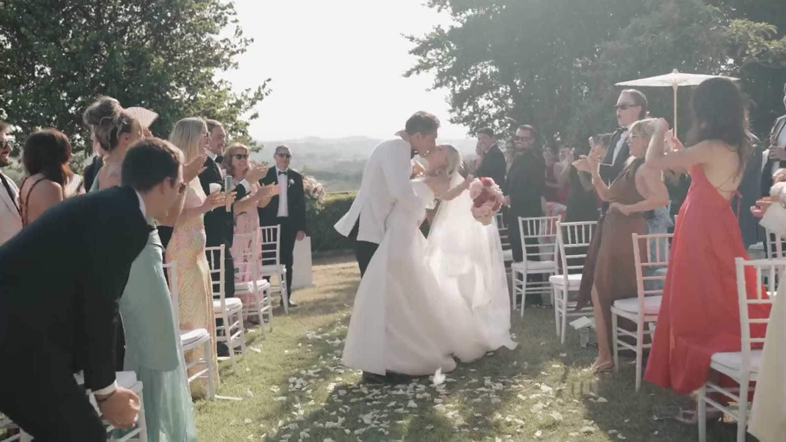 The newlyweds kissing as they walk back down the aisle through their guests